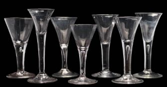 Seven wine glasses: each trumpet shaped bowl tapering into a straight stem,