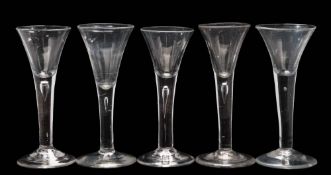 Five wine glasses: each trumpet shaped bowl tapering into a straight stem, incorporating a tear,