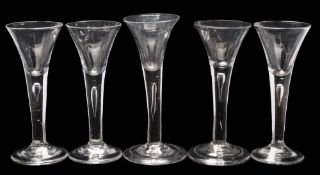 Five wine glasses: each trumpet shaped bowl tapering into a straight stem, incorporating a tear,