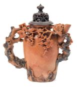 A Chinese soapstone wine pot: carved with flowering prunus and rockwork,15 cm and wood cover.