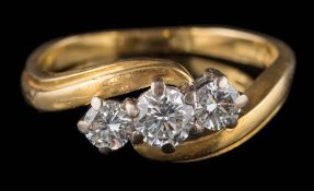 An 18ct gold and diamond three-stone cross-over ring: the round,