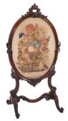 A Victorian carved rosewood oval firescreen:, with rocaille, C-scroll and acanthus leaf cresting,