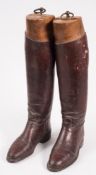 A pair of brown leather riding boots and wooden boot trees:..