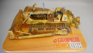 A diorama of a Caterpillar Bulldozer D8H: mounted on a wood base.