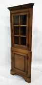 20th century oak corner display cabinet with glazed door enclosing three shelves, above cupboard