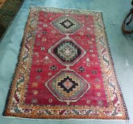 Red ground Eastern style floor rug with three central stepped medallions to a stepped border,