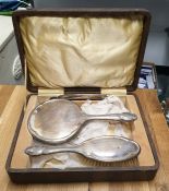 Silver-backed hairbrush and a matching silver-backed hand mirror and comb, in fitted case