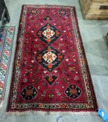 Red ground Eastern rug with two black ground interlinked central medallions, the field supporting