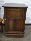Oak single door cabinet with canted sides flanking the panelled and beaded decorated door, enclosing