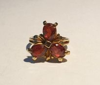 9ct gold and garnet ring set with three teardrop shaped mixed cut garnets, in a flowerhead design,