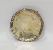 Small salver, circular with serpentine gadrooned border on four supports, claw and ball feet, 20.