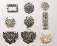 Silver-coloured buckle of elaborate pierced design around a central seated figure, a paste