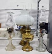 Two brass paraffin lamps, and two other paraffin lamps, one with moulded glass base showing flying