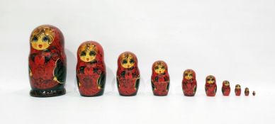 Russian Matryoshka doll painted in bright colours reserved on a red ground enclosing nine smaller