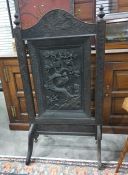 Ebonised firescreen in the Eastern taste, the arched top featuring frieze carving of birds amongst