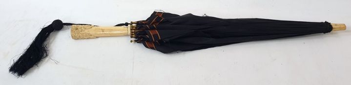 A vintage ivory mounted silk parasol, the carved ivory handle with flowers with a wooden and brass