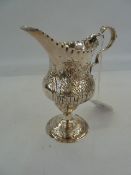 George III silver cream jug, pyraform and later repousse garden scene, on circular foot, London