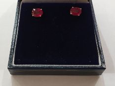 Pair of white metal heat-treated ruby stud earrings, each set oval cut stone