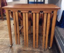 Teak coffee table with four folding coffee tables slung under, the whole on casters