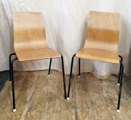 Two plywood shaped dining chairs on four metal legs, the plywood sheet bent to form the seat and