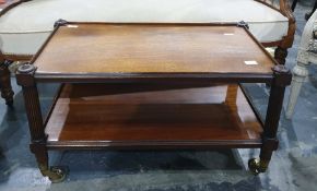 Reproduction mahogany two-tier coffee table on reeded supports, brass caps and castors