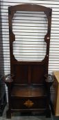 Early 20th century oak hall-stand, the back with assorted coat hooks above the settle, arm rests
