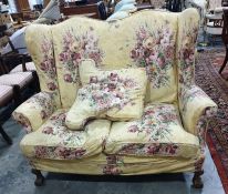 Early 20th century suite comprising two wingback chairs and two-seater sofa, raised on claw and ball