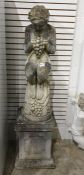 Reconstituted stone garden ornament of a Bacchus holding grapes, on a square stone plinth, 136cm