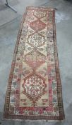 Cream ground runner with five interlocking central hooked medallions, with foliate decoration,