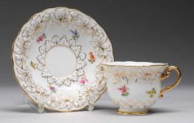 Tasse mit UTWeiß, glasiert. Floraler Reliefdekor. Polychrome Bemalung mit Streublüten. Goldränder u.