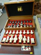 Modern mahogany cased chess set by Isis Ceramics Ltd, black and white biscuit porcelain with gilt