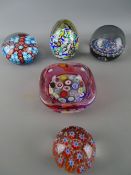 Four vintage millefiori decorated paperweights and a similar bowl with cranberry tint
