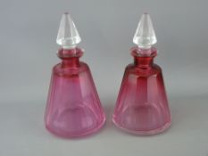 Pair of conical cranberry glass scent bottles with facet cut clear stoppers