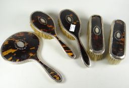 A silver & tortoiseshell five-piece dressing table set with spider web framed oval monogram