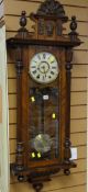 An antique walnut veneer Vienna-type wall clock of architectural form with Roman numeral dial,