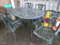 A green metal garden table with four chairs