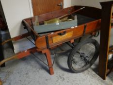 A wooden hand cart with metal chassis and pneumatic tyres on spoked wheels, bears plaque for