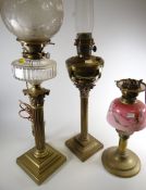Three antique brass oil lamps, one having been converted for electric use