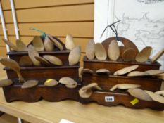 Two antique stepped oak wooden spoon holders with a selection of lightwood carved wooden spoons