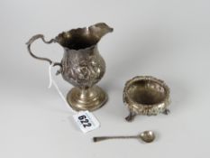 A Victorian silver relief decorated helmet cream jug together with a relief decorated silver salt on