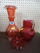 Good antique cranberry glass plain handled jug, a cranberry glass narrow necked vase and a small