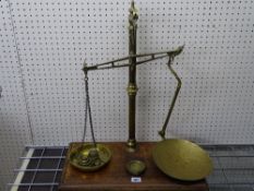 Set of brass provision scales on a mahogany base with several weights