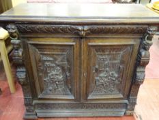 A CONTINENTAL CARVED OAK SIDEBOARD with lion mask and figural detail, the door panels showing tavern