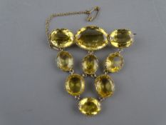 A YELLOW METAL BROOCH of nine graduated oval amber stones