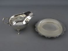 A SILVER SAUCE BOAT with scroll handle on three hoof feet and a hallmarked butter dish stand with