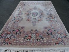 A GOOD CHINESE WASHED WOOLLEN FLORAL PATTERNED CARPET on a blush cream ground with tasselled ends,