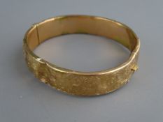 A NINE CARAT GOLD HALF BRIGHT CUT HOLLOW BANGLE (some damage), 14.5 grms