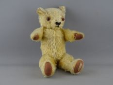 AN APPEALING BABY TEDDY BEAR, 30 cms long with glass eyes, stitched snout and sewn paws with