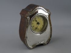 A WOODEN ENCASED MANTEL CLOCK, the shaped front around the circular dial in silver, Birmingham 1944
