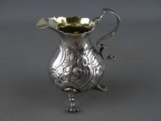 A VICTORIAN SILVER CREAM JUG with raised swan and floral decoration and front vacant cartouche,